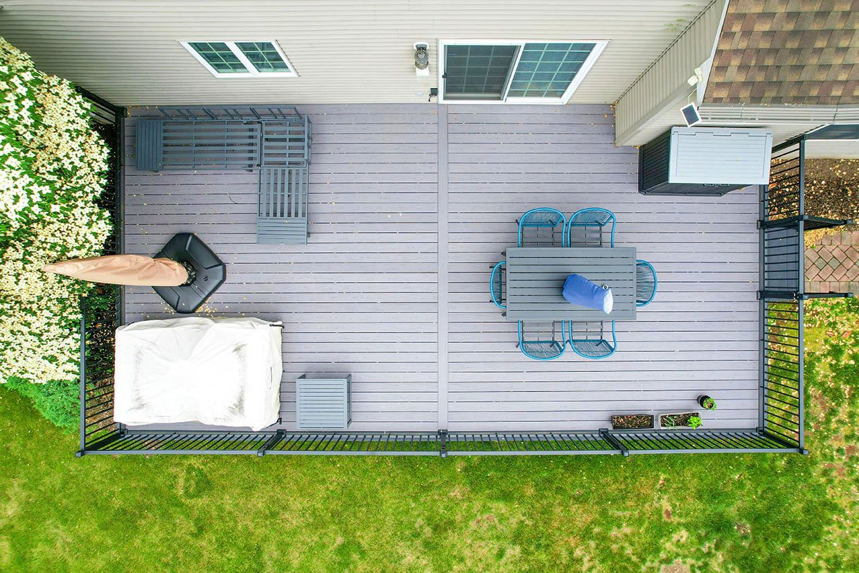 Aerial view of a rectangular grey composite deck layout showing distinct lounging and dining zones separated by a central walkway.