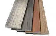 Four planks of composite decking samples fanned out, showing color variations in gray, charcoal, and brown wood grains.