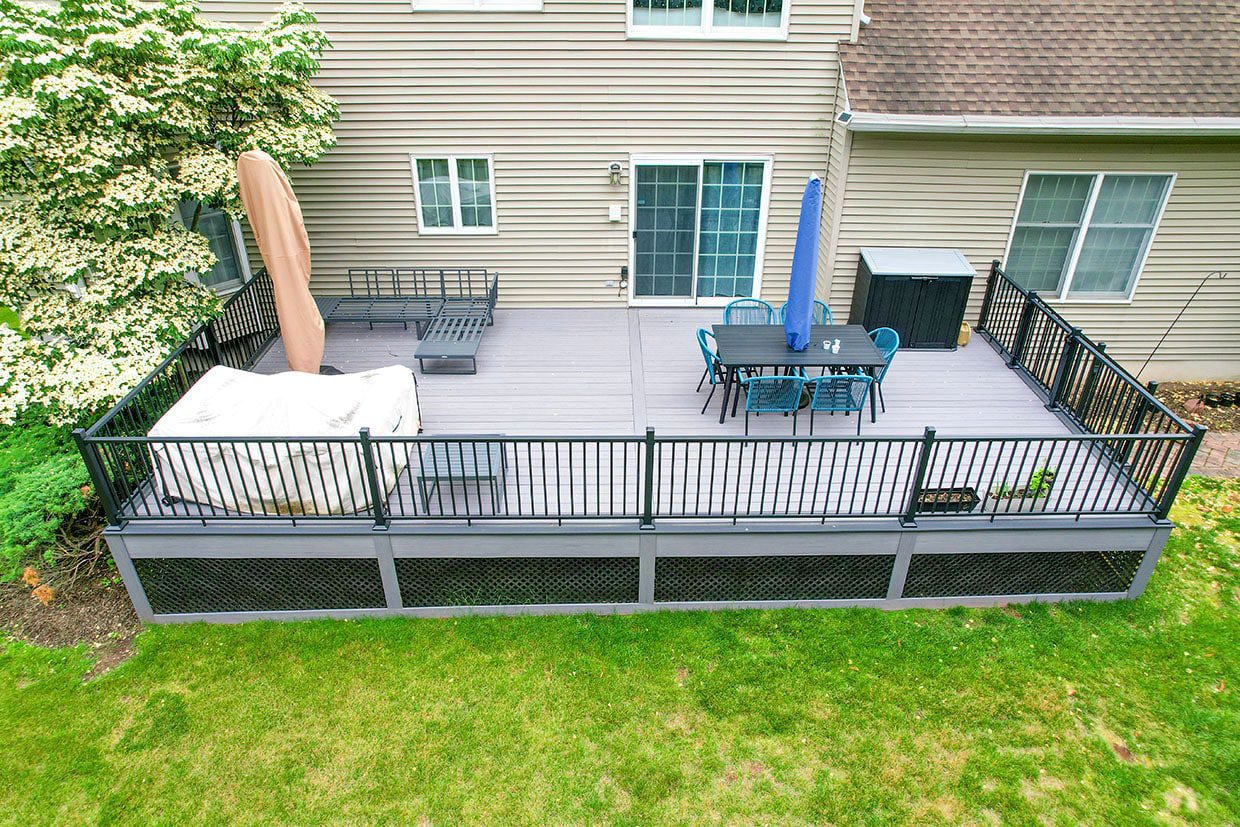 Elevated view of a spacious grey composite deck featuring black metal railings and dining furniture, exemplifying modern outdoor living spaces in Covington.