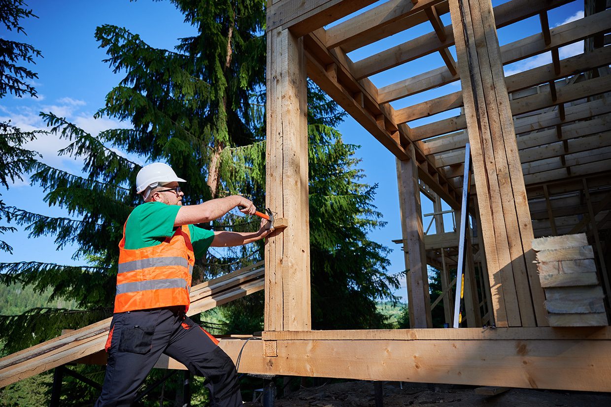 Construction worker installing heavy timber framing for a project by custom deck builders.