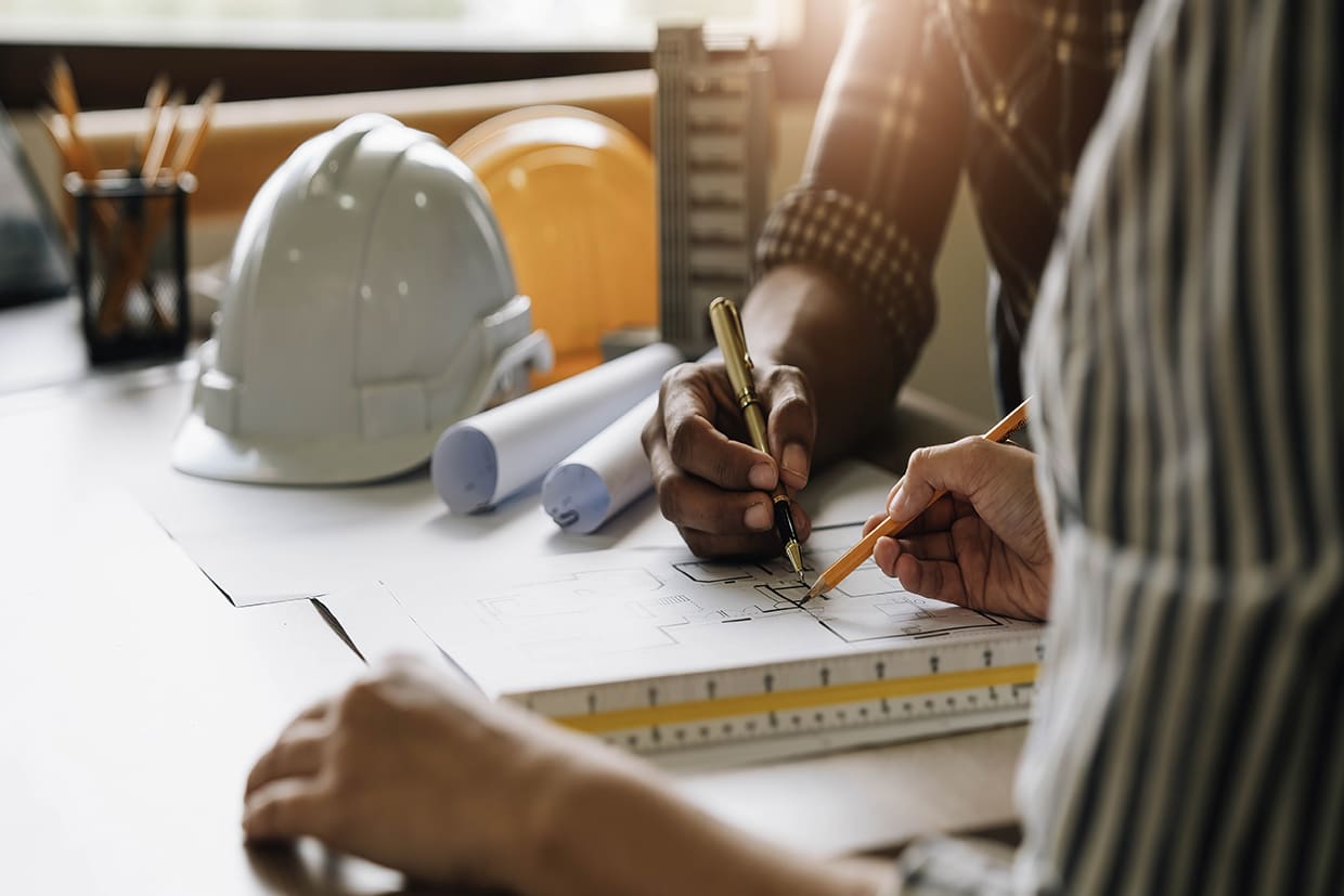 Two people reviewing architectural blueprints at a desk, representing the planning phase of hiring professional deck builders.