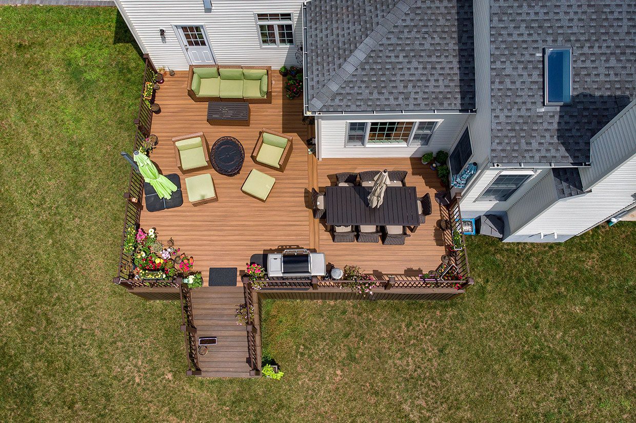 Aerial view of a spacious brown composite deck layout featuring a dining table, lounge seating, and a grill area.