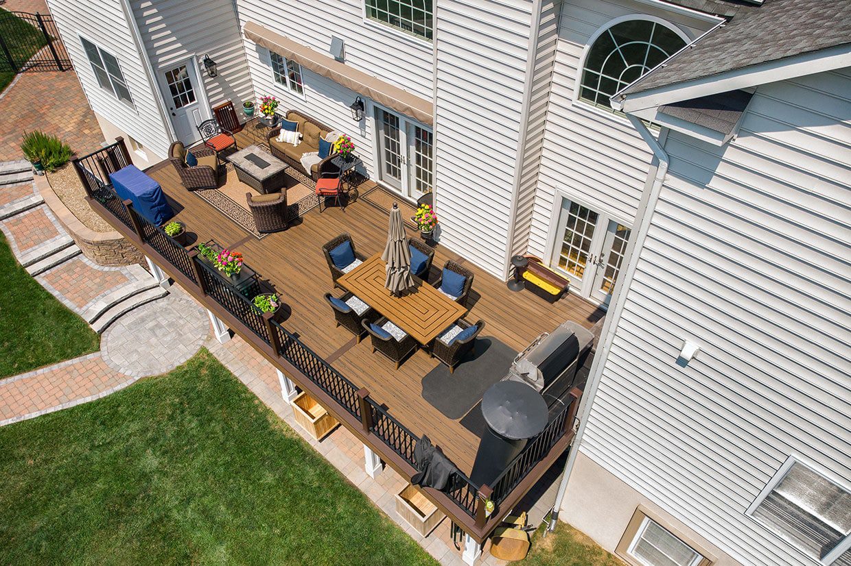 Aerial view of a spacious multi-level backyard deck attached to a white suburban home.