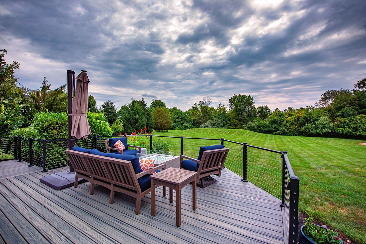 Outdoor furniture set on a grey deck overlooking a large green lawn.