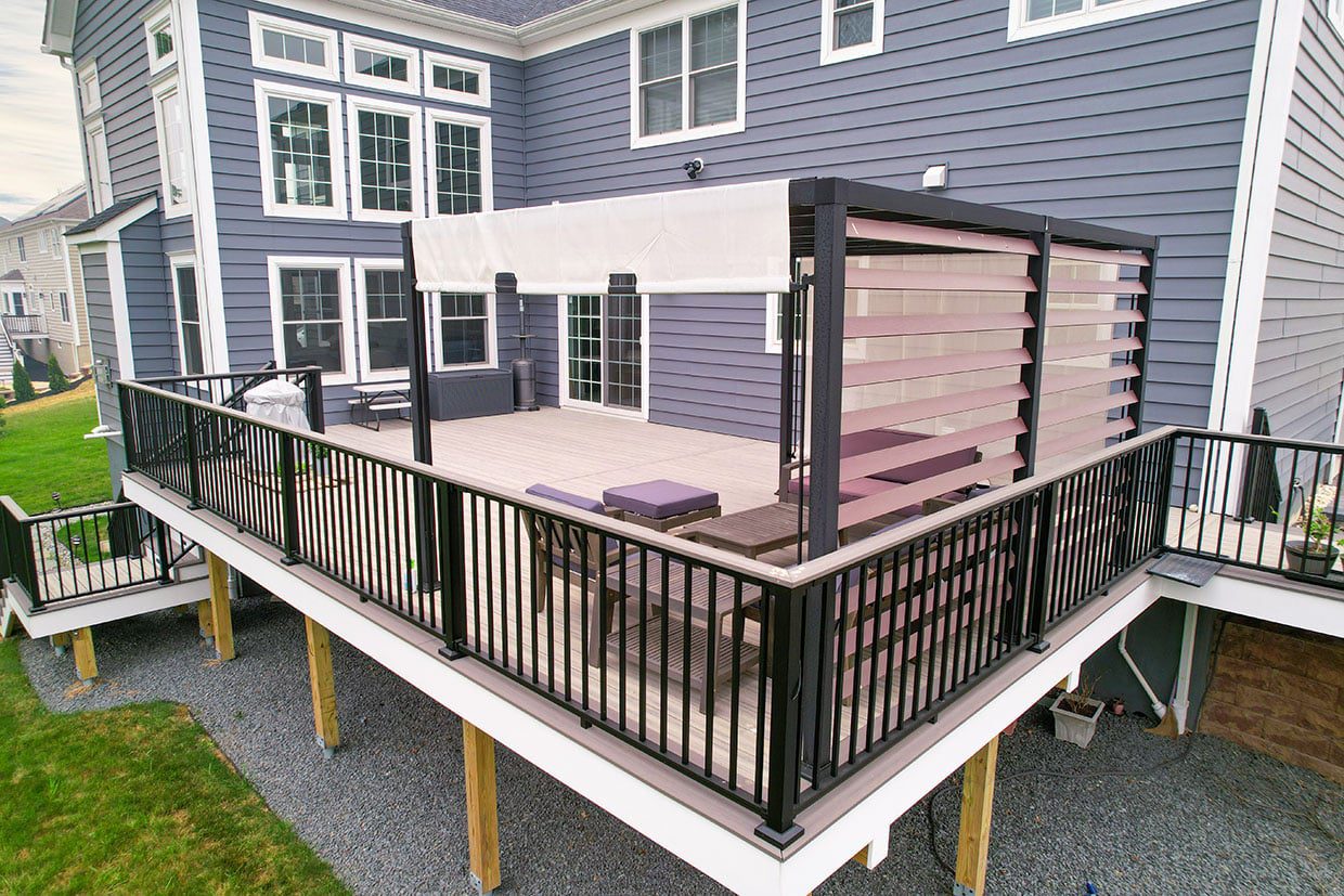 An elevated composite deck featuring black railings and a modern pergola for deck shade with adjustable privacy screens.