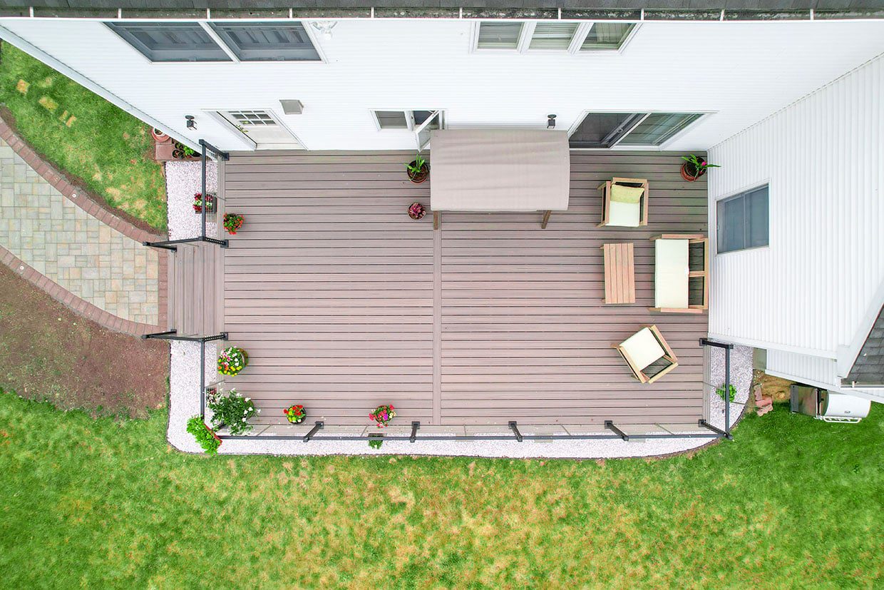 Aerial view of a rectangular grey composite deck with simple furniture and white crushed stone landscaping.