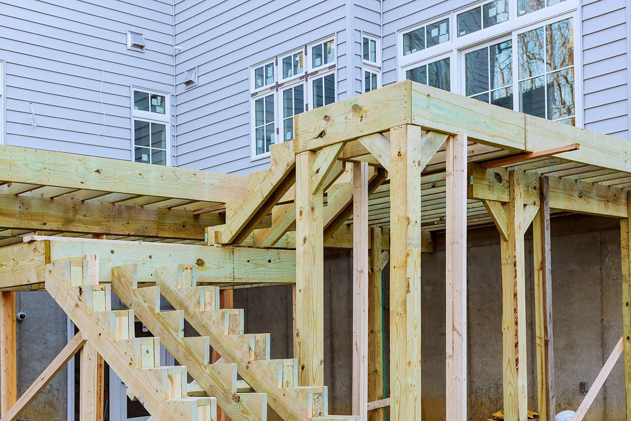 Wooden structural framing and stair stringers for a tiered deck construction project.