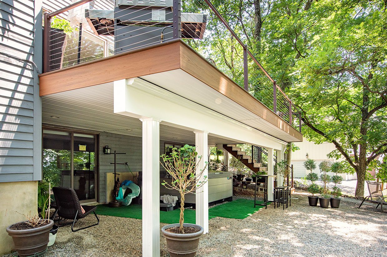 Two story deck ideas utilized to create a shaded lower patio with a hot tub.