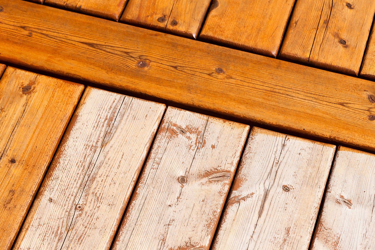 A close-up comparison showing weathered, peeling gray wood planks next to freshly cleaned and stained timber, essential for a custom deck design upkeep.
