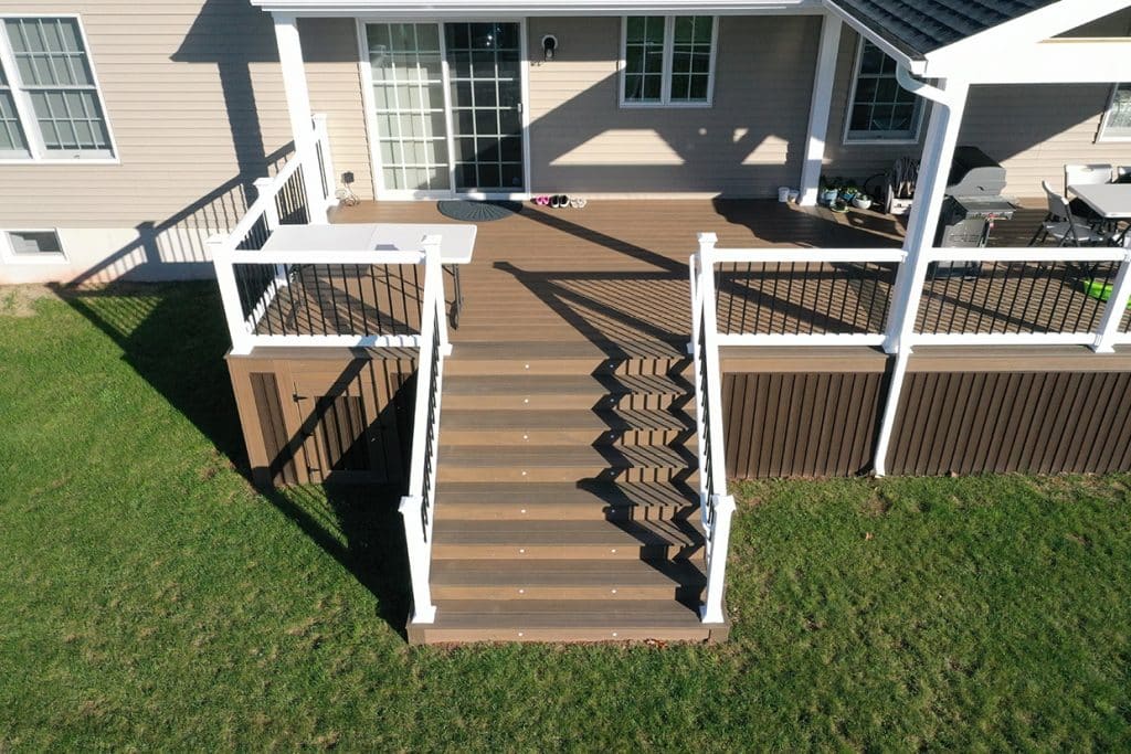 An aerial view of a pristine backyard featuring low maintenance decking with white railings, often considered among the best deck materials for durability.