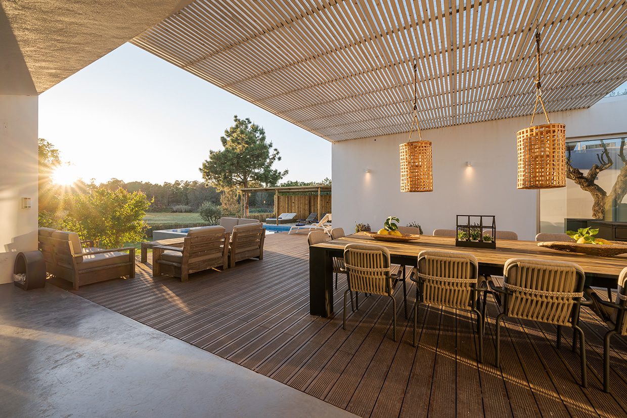 Outdoor dining area showing sunlight filtering through adjustable slats, visually representing the practical Benefits Of Louvered Roofs.