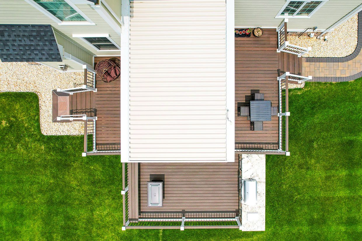 Aerial view of a multi-level deck layout featuring a covered center, dining zone, and grilling station.