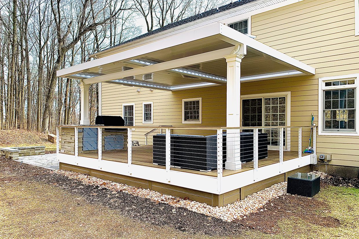 Covered composite deck design featuring a weather-resistant patio roof, sleek cable railings, and a built-in outdoor kitchen station that defines functional outdoor living spaces.