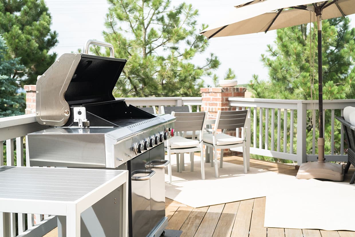 Stainless steel gas grill on a sunny deck featuring weather-resistant materials, illustrating functional modern deck designs for outdoor entertaining.