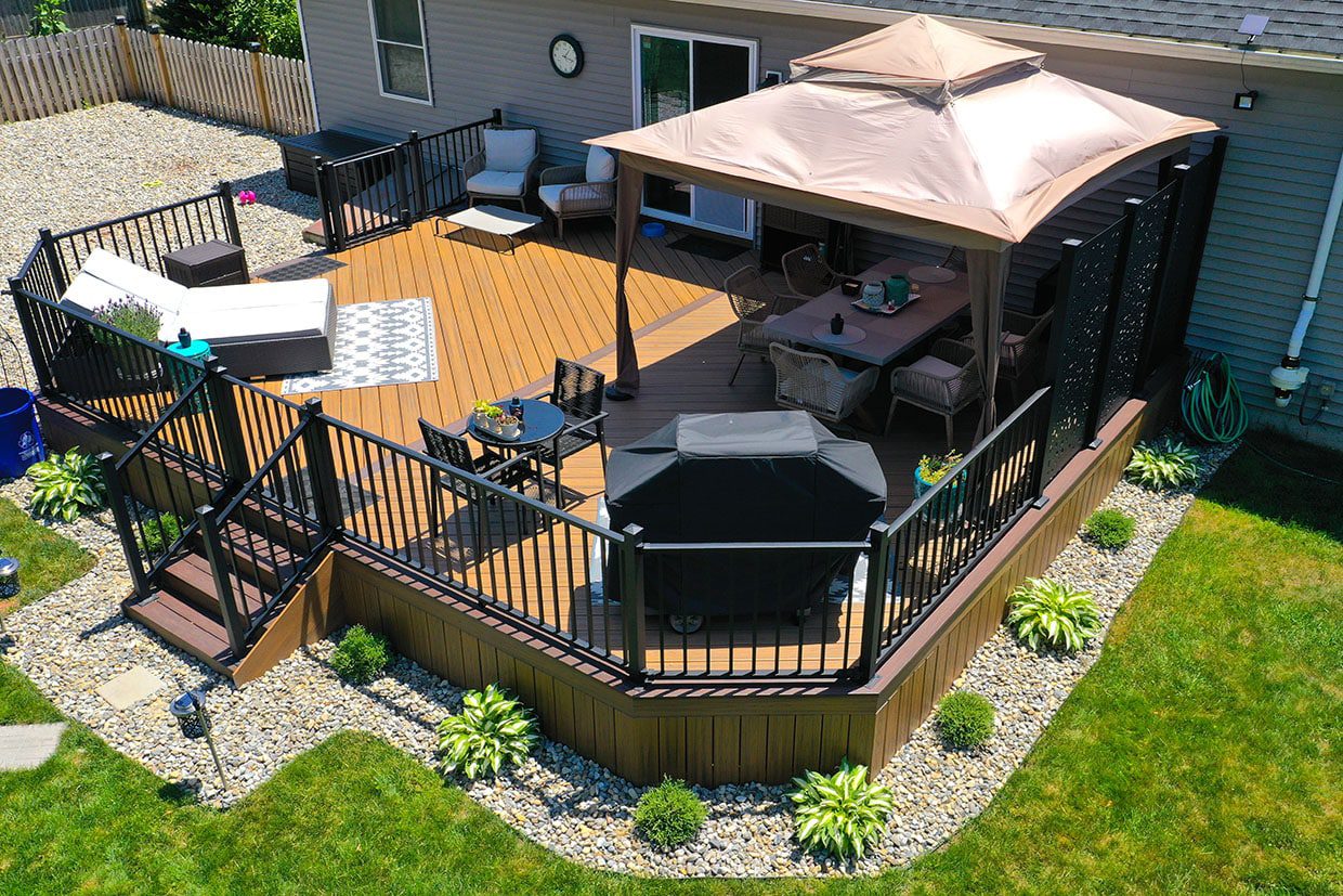 A high-angle view showcasing one of the greatest deck designs for small backyards, featuring a portable gazebo, dining area, and lounge space on a custom composite deck.