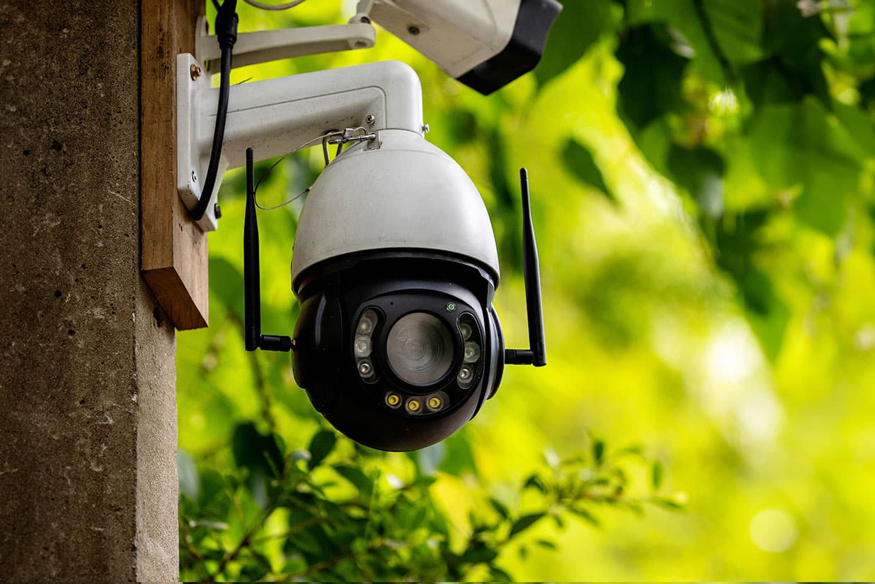 Close-up of a wireless security camera mounted on a wooden post, a crucial element of safety in modern deck designs and smart home integration.