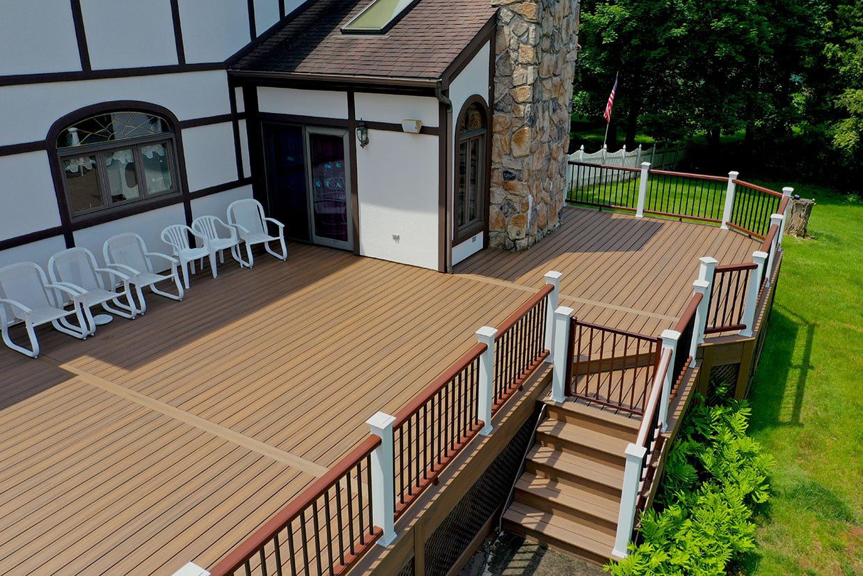 Expansive multi-level patio built using sustainable decking materials featuring white railings and classic outdoor seating.