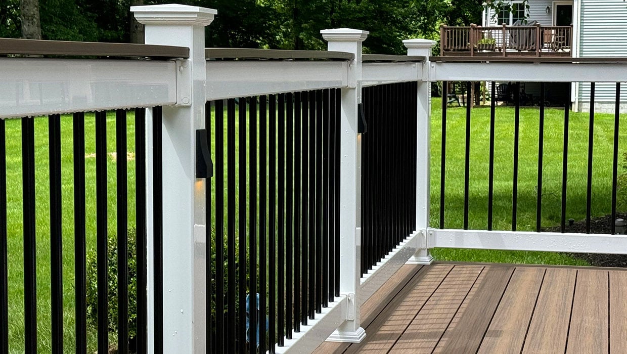 Close-up of white vinyl posts with black aluminum balusters and integrated post lighting, suitable for both modern and traditional deck styles.