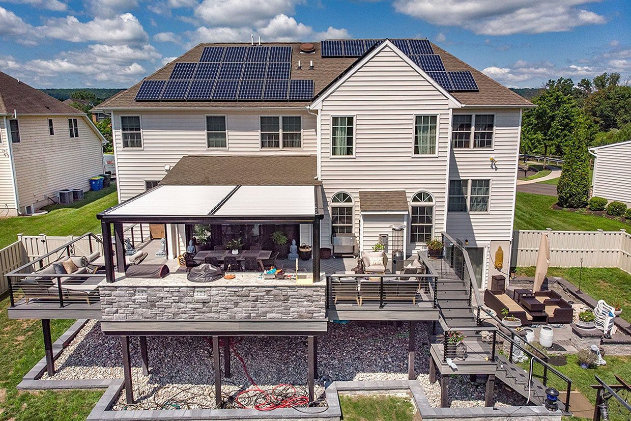 Luxury multi-level outdoor living space featuring a covered dining area, stone veneer details, and a lounge zone.