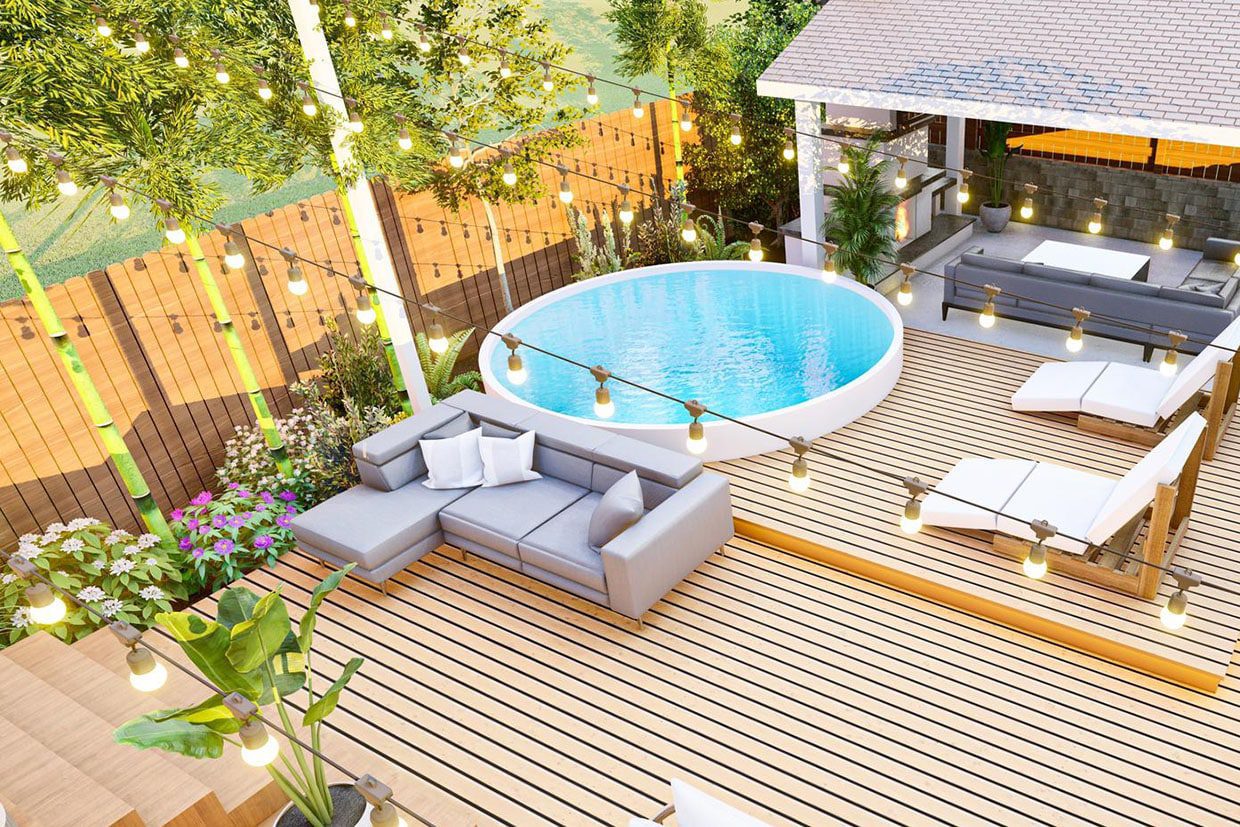 Aerial view of a luxurious backyard featuring a round, built-in hot tub surrounded by a multi-level wooden deck, modern sectional furniture, and string lights, illustrating comprehensive outdoor spa deck ideas.
