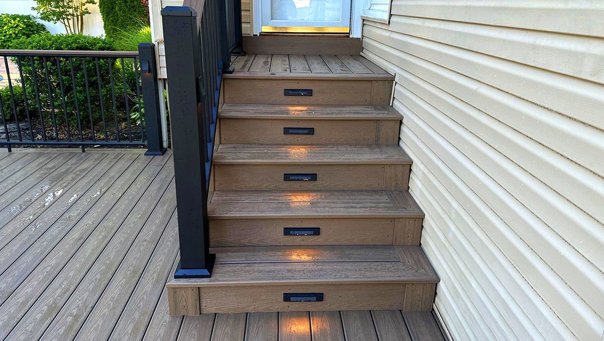 Brown composite deck stairs featuring built-in riser lights for safety, a key element in personalized deck plans for accessibility.