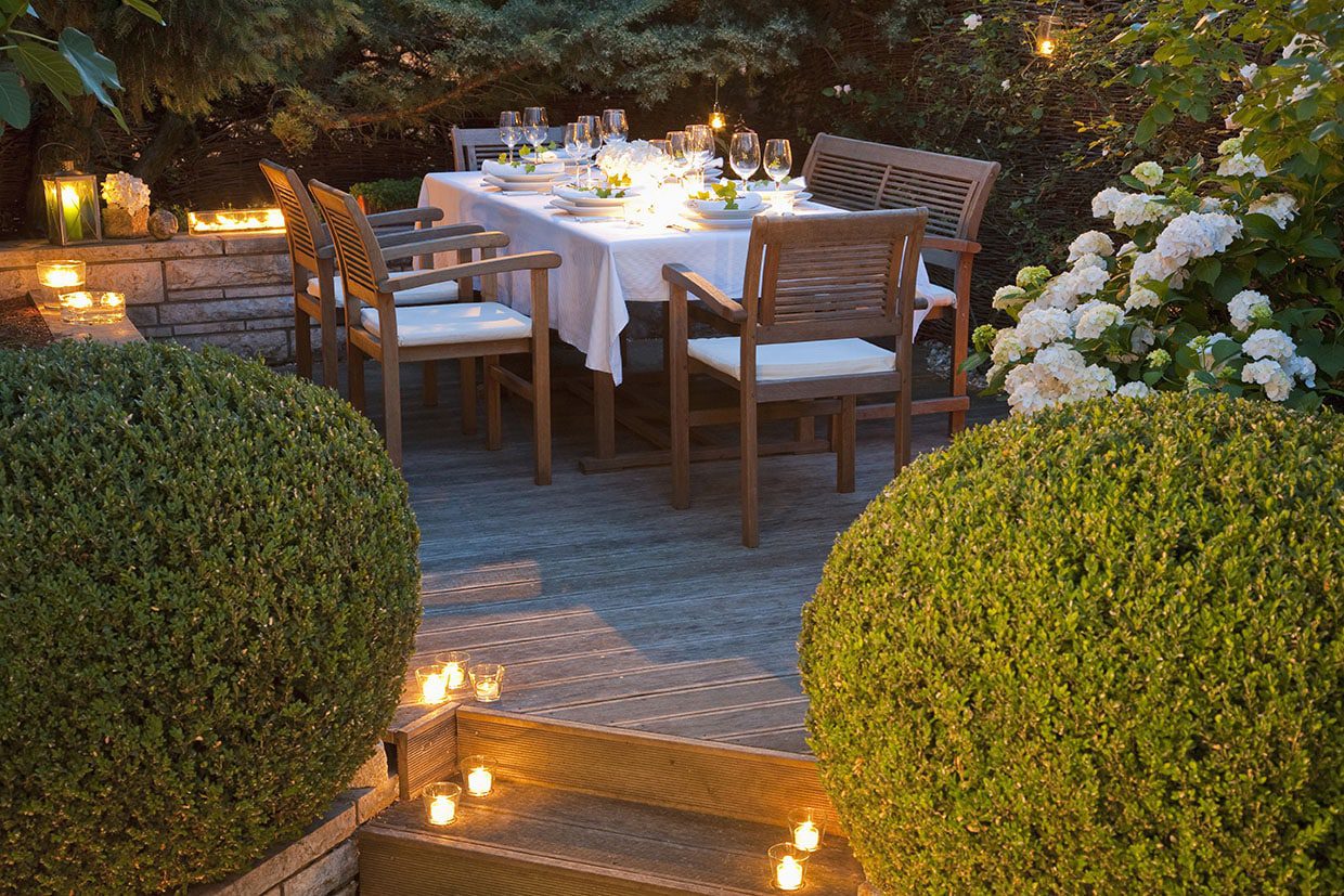 Elegant outdoor dining table set with a white tablecloth and wine glasses, surrounded by blooming hydrangeas and candlelit steps.