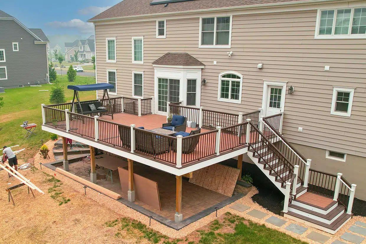 How to Build a Deck Large, finished two-story composite deck with white railings and stairs creating a spacious outdoor living space.