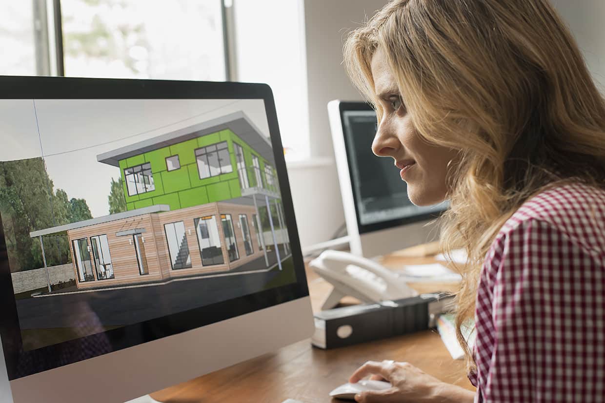 Laptop displaying digital free deck plans and a wireframe architectural sketch on an outdoor wooden table.