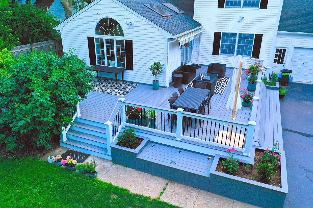 Grey painted deck featuring built-in planters, storage benches, and a patio dining set.