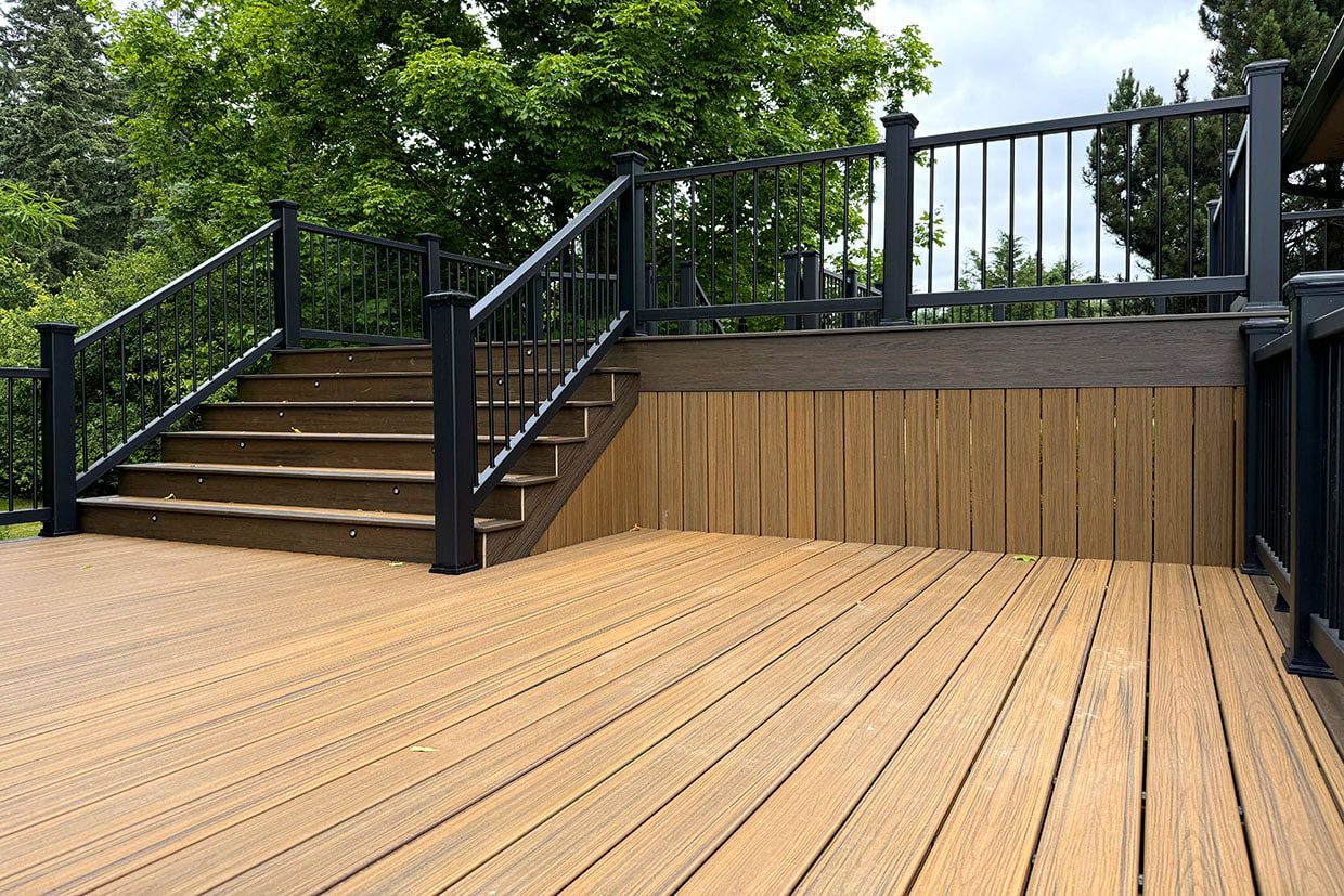 Low-angle view of brown composite decking steps with built-in riser lights and black aluminum railings.