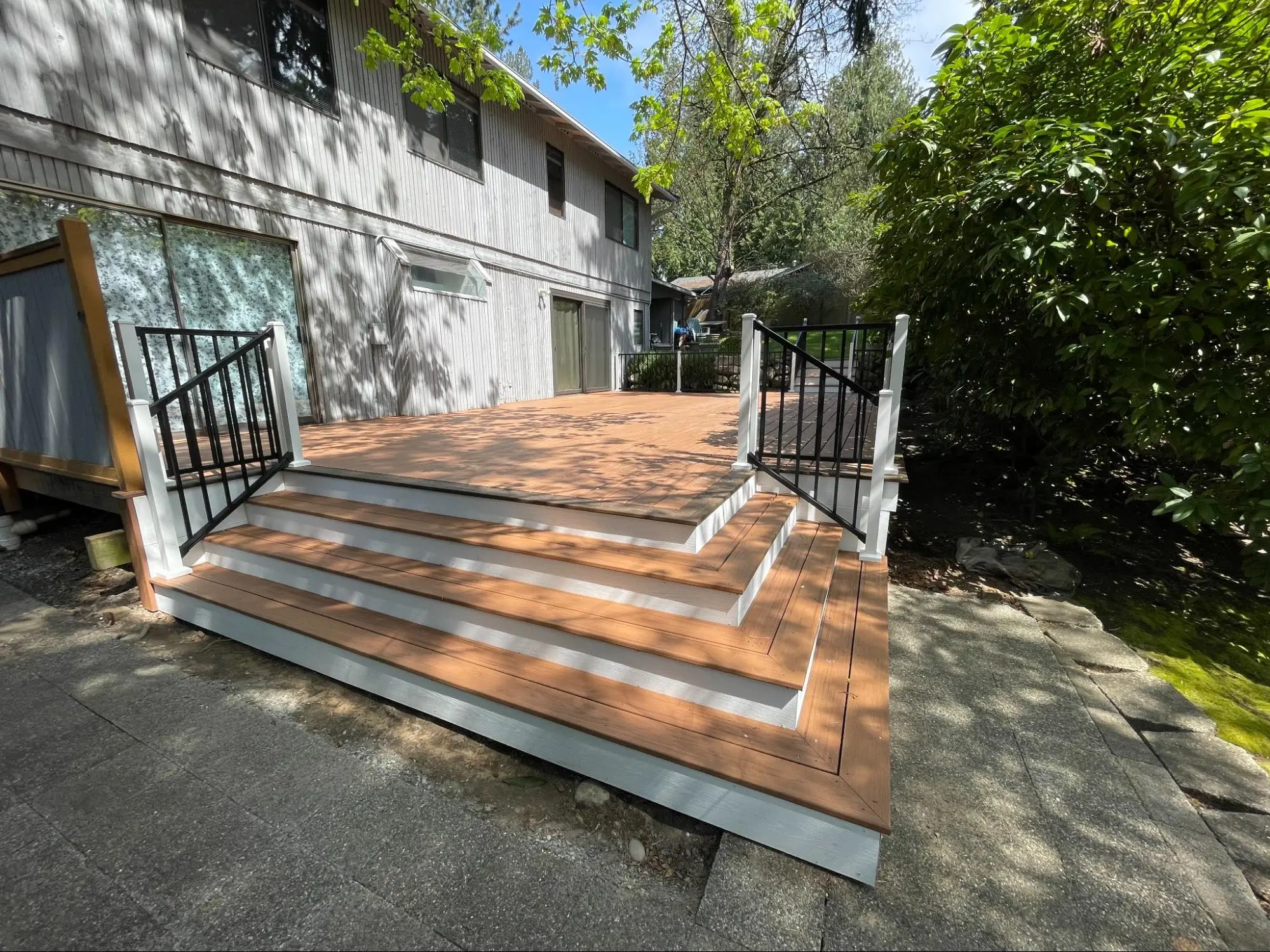 Beautiful new deck featuring light wooden planks and sleek black railings, providing a spacious outdoor area for gatherings.