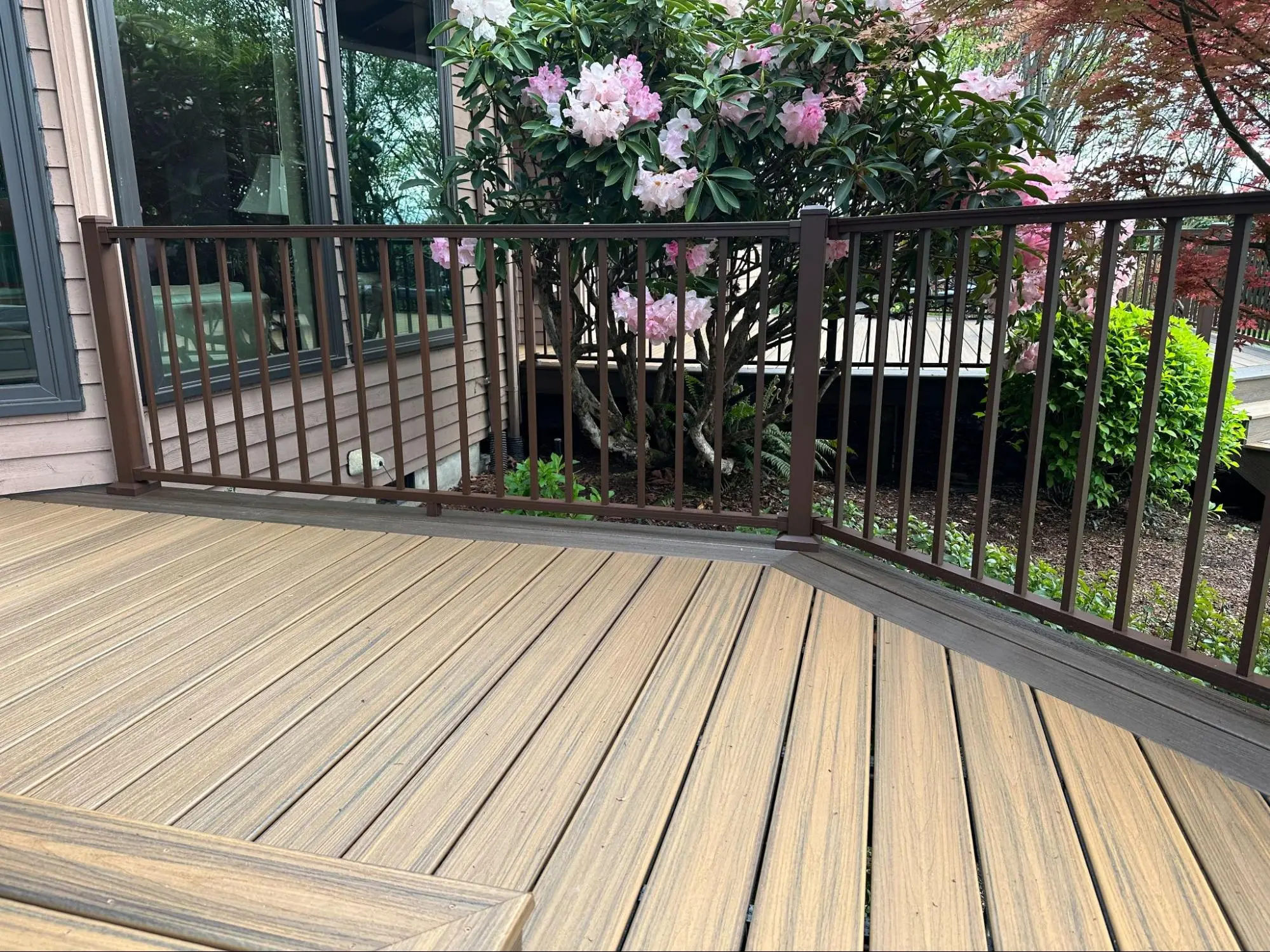 Freshly built deck with a modern design, featuring wooden steps and black railings, perfect for outdoor leisure.