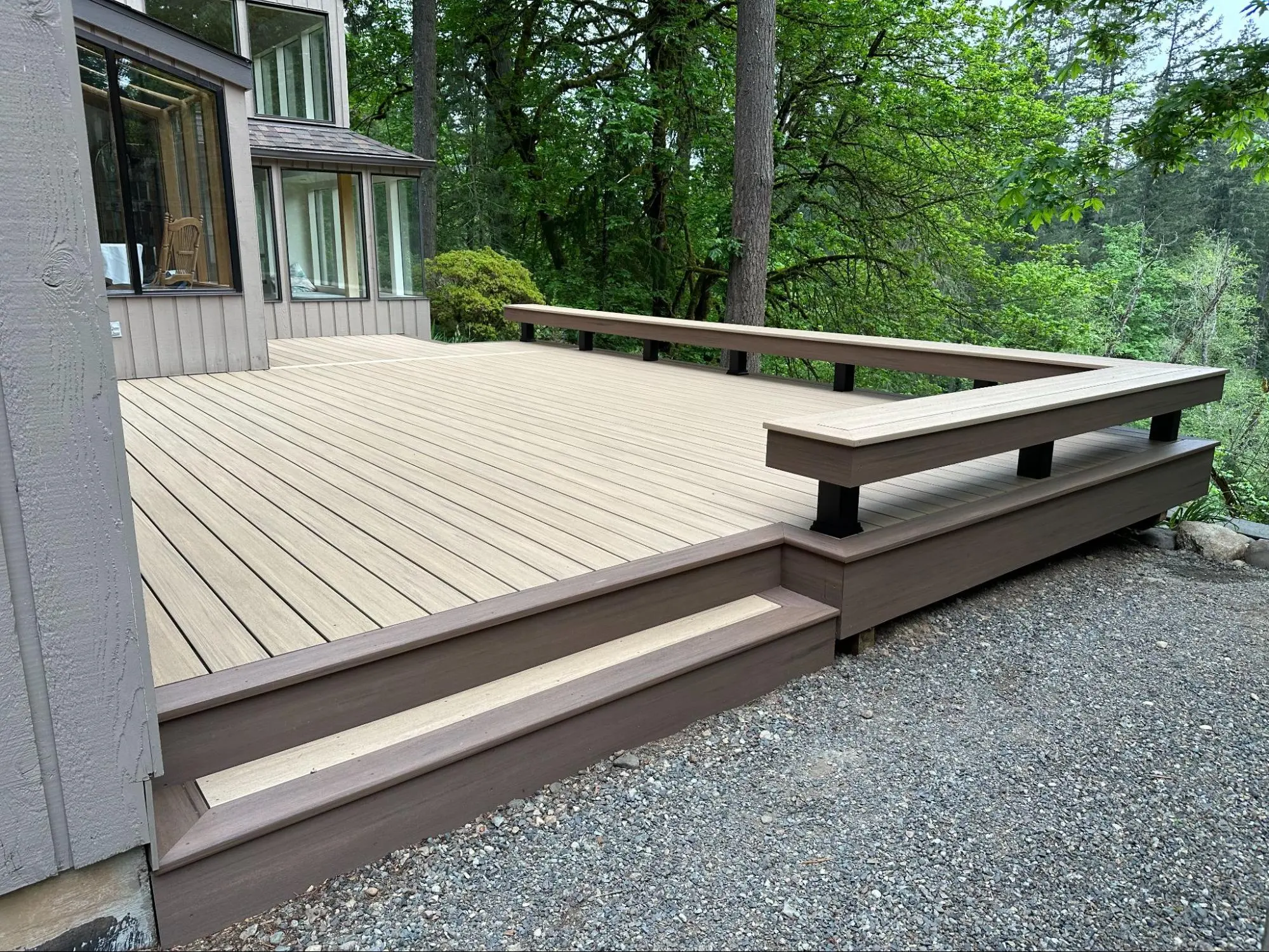 A newly constructed deck with modern wooden planks and a stylish brown railing, offering a fresh outdoor space for relaxation.