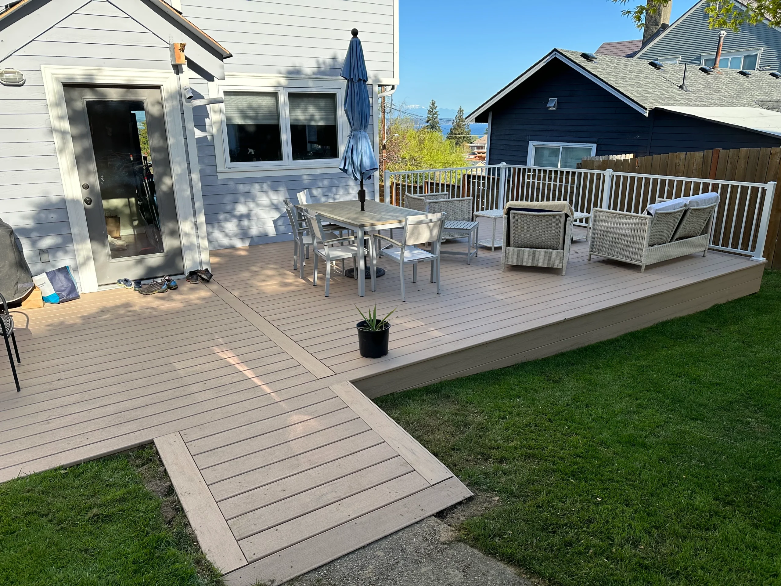 A backyard deck featuring a dining area, white railings, and an accessible ramp, designed by custom deck builders Seattle homeowners trust for functionality.