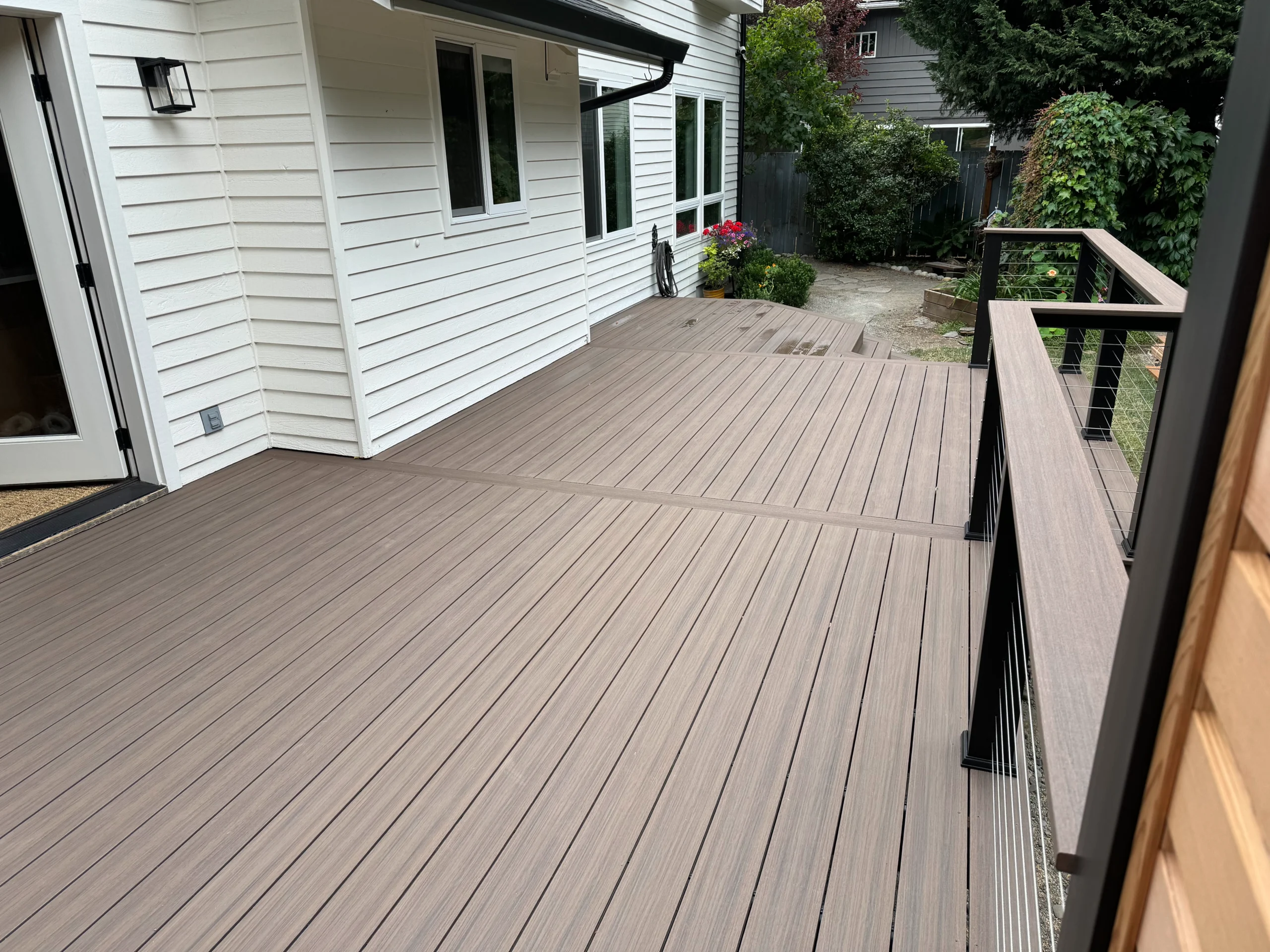 A beautifully restored deck featuring composite flooring and modern black railing. Ideal for a seamless outdoor living space. Restore decks.