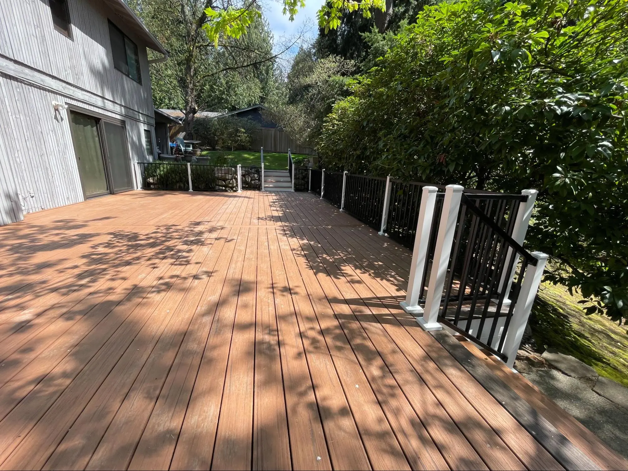 Newly built deck with wooden steps and black railings, creating a stylish and functional outdoor living area.
