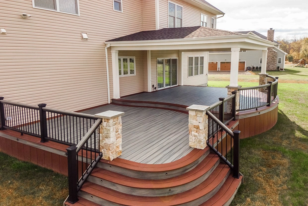 A stunning composite deck with a curved staircase, showcasing the elegance of deck design, relevant to Deck Resurfacing vs Replacement Washington