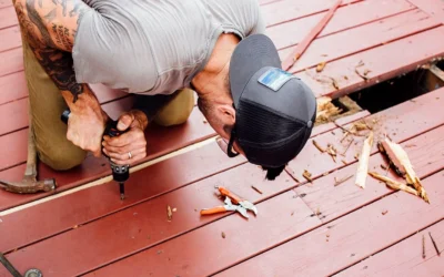A skilled deck builder using a drill to inspect and repair a deck, a sign of the Best Deck Builders Near You.
