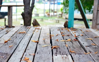 An old, worn-out deck with gaps and leaves, showing signs of aging in need of deck resurfacing Seattle services.