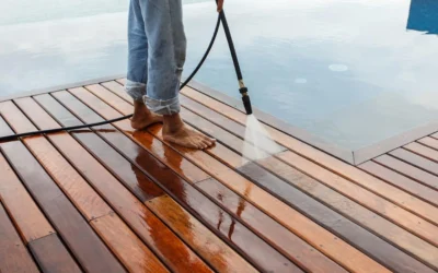 A person cleaning a wooden deck with a power washer, showing maintenance for Composite Deck Installation.