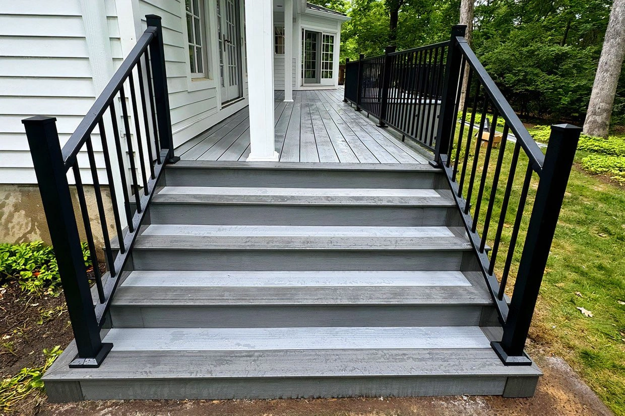 A completed composite deck with stairs and black railings, showcasing a durable Composite Deck Installation.