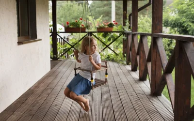 A young girl enjoying a swing on a deck with sturdy railings, emphasizing the need to Replace Deck Railings for safety.