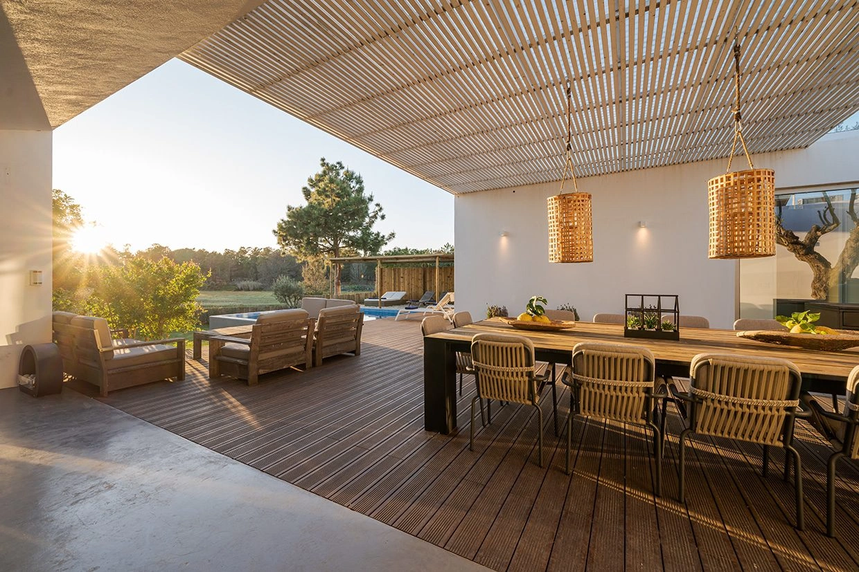 A serene outdoor space featuring a wooden dining area, with soft lighting and natural surroundings, embracing minimalist zen deck design principles.