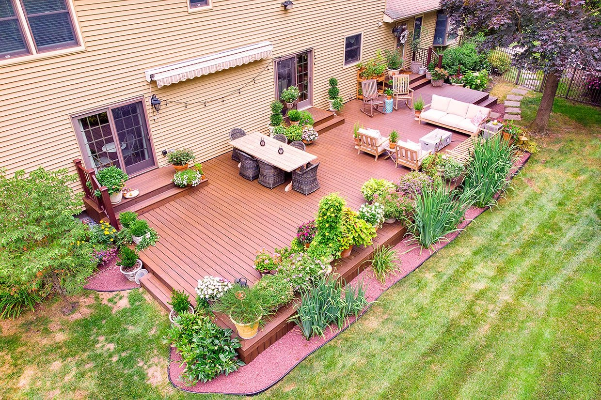 deck restore A restored deck surrounded by flowers and greenery, showcasing a well-maintained outdoor space.