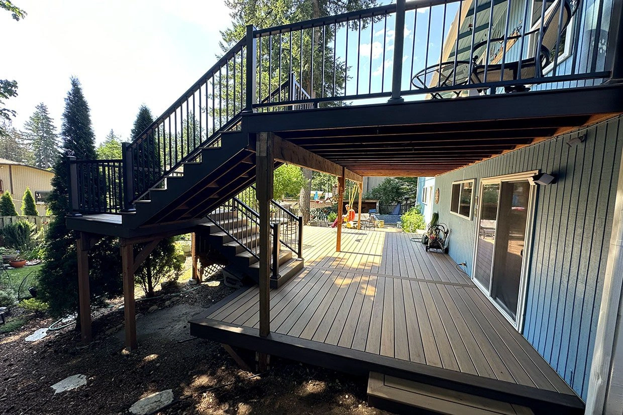 deck restore A beautifully restored deck with a set of stairs and modern black railing.