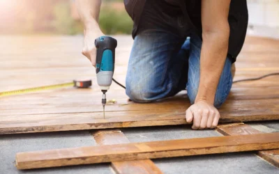 A person using a drill to secure wooden boards during deck restore.