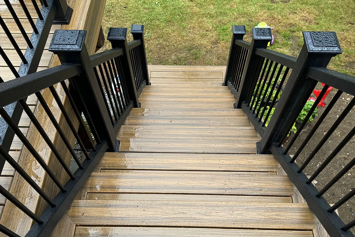 Sturdy composite deck steps with black railings, offering moisture resistance and deck waterproofing benefits.