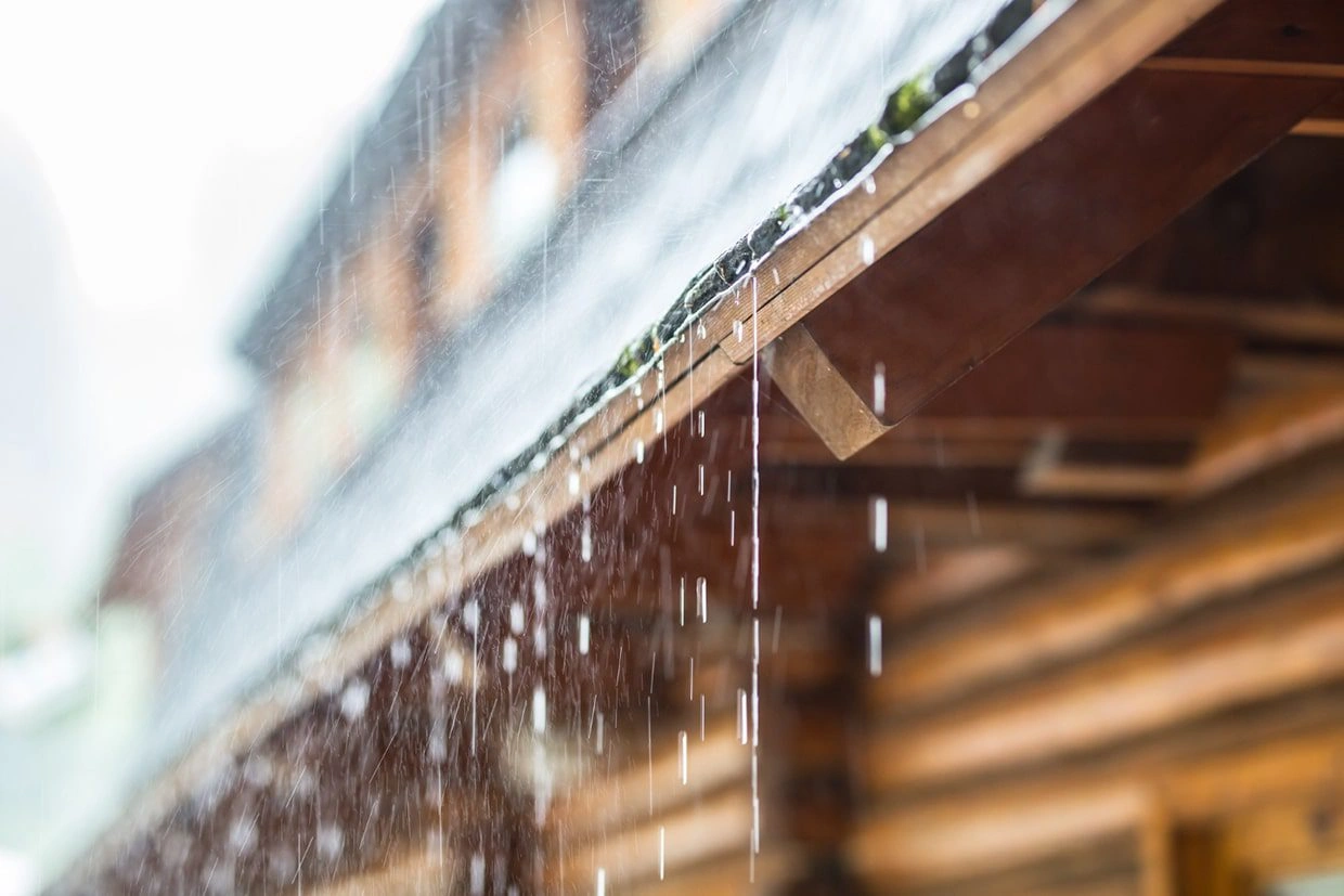 Rainwater flowing off a roof, showcasing the impact of weather conditions on outdoor structures and the importance of deck waterproofing.