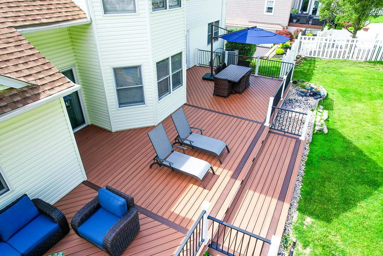 A multi-level backyard pet deck features ample seating, an umbrella, and black railings, offering a secure outdoor space.
