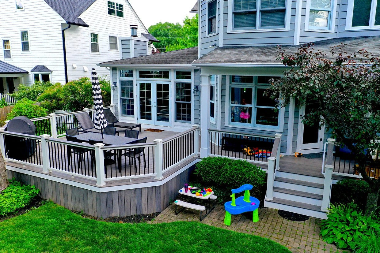 Completed, custom-shaped composite deck featuring a dining area, grill, and white railings, illustrating high-quality work by a deck contractor in Bellevue.